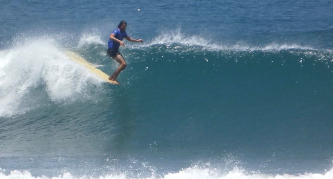 Surfer gliding across a glassy blue wave on a longboard