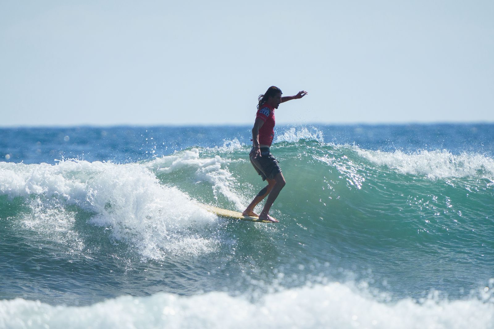 Chelo surfing a clean wave on a longboard